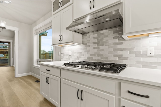 kitchen with stainless steel gas cooktop, light countertops, white cabinets, and under cabinet range hood