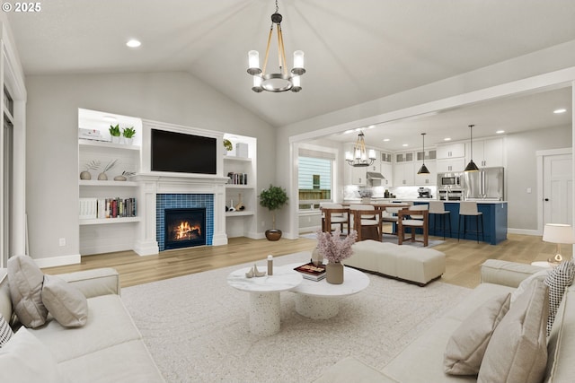 living room featuring a chandelier, lofted ceiling, a tile fireplace, recessed lighting, and light wood-type flooring