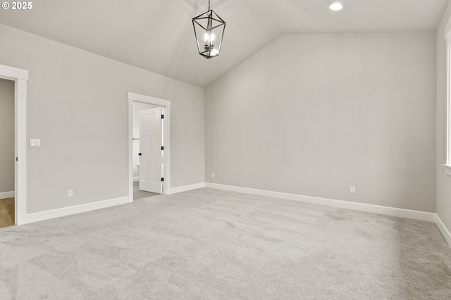 unfurnished room featuring carpet floors, an inviting chandelier, baseboards, and vaulted ceiling