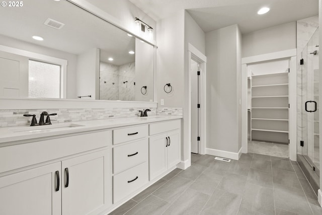 bathroom featuring backsplash, visible vents, a sink, and a spacious closet