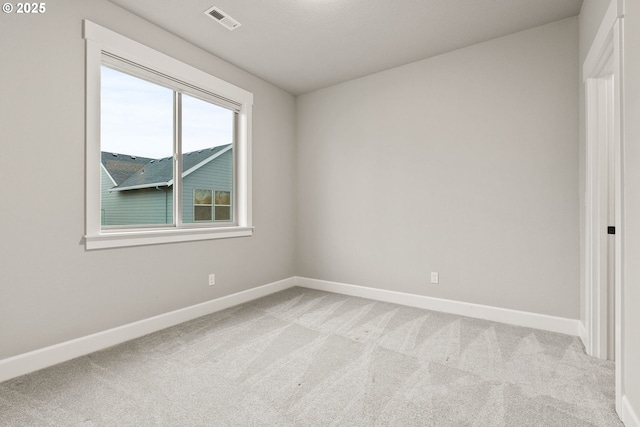 spare room with light carpet, visible vents, and baseboards