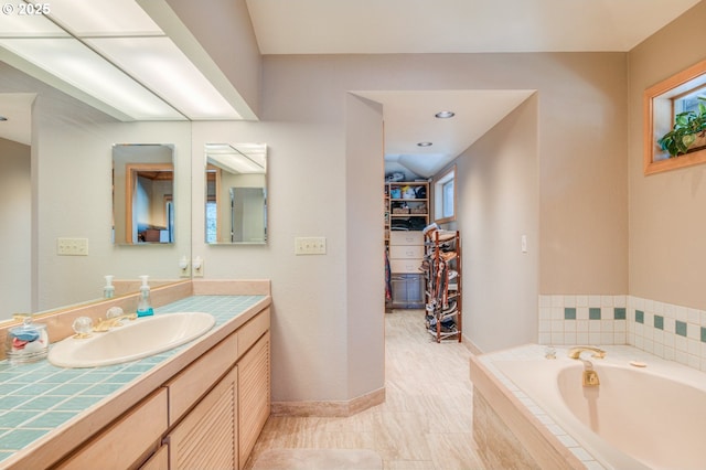 full bathroom with a bath, vanity, a walk in closet, and baseboards