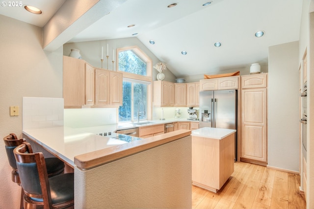 kitchen featuring light brown cabinetry, appliances with stainless steel finishes, a peninsula, and a sink