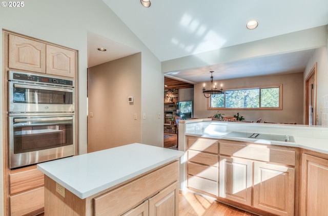 kitchen featuring double oven, light brown cabinetry, and light countertops