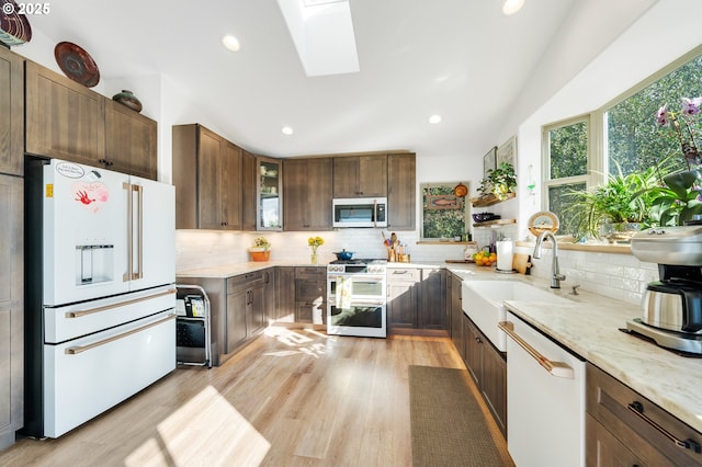 9065 8th St, Bay City, OR 97107 - kitchen with appliances with stainless steel finishes, a skylight, a sink, vaulted ceiling, and backsplash