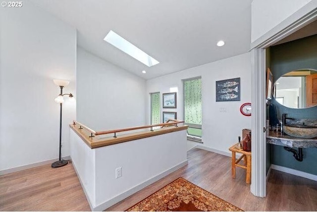 9065 8th St, Bay City, OR 97107 - hallway featuring a skylight, wood finished floors, lofted ceiling, a sink, and recessed lighting