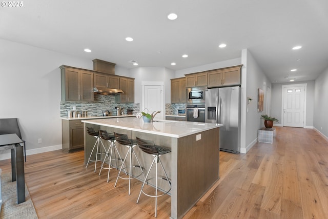 15180 SW Harveys View Ave, Tigard, OR 97224 - kitchen with stainless steel appliances, under cabinet range hood, tasteful backsplash, light wood-style floors, and recessed lighting
