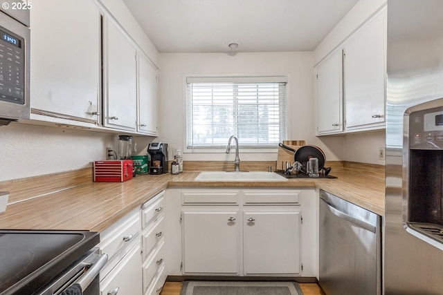 kitchen with sink, white cabinets, and appliances with stainless steel finishes