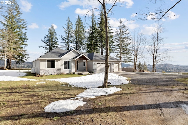 view of front of home with an attached garage, stone siding, and driveway