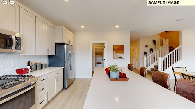 kitchen with appliances with stainless steel finishes, light wood-type flooring, tasteful backsplash, light countertops, and recessed lighting