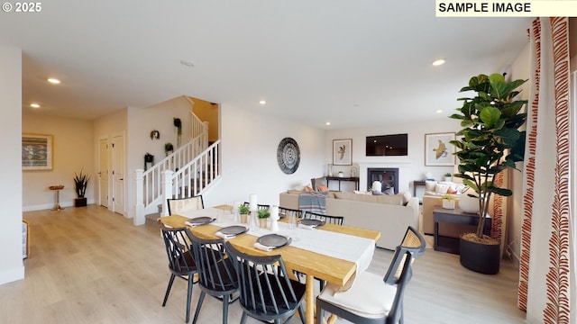 dining area with stairs, light wood-style floors, recessed lighting, a glass covered fireplace, and baseboards