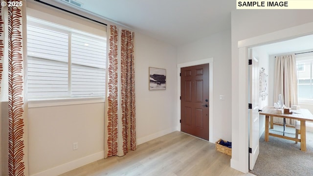 foyer entrance with light wood-style flooring and baseboards