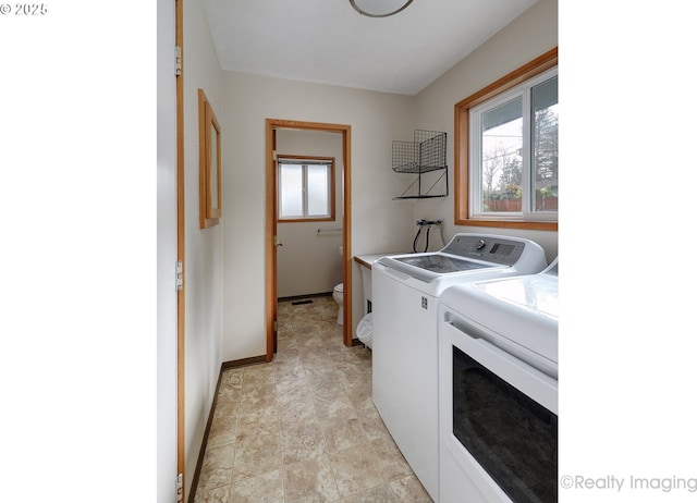 clothes washing area featuring washing machine and clothes dryer, cabinet space, and baseboards