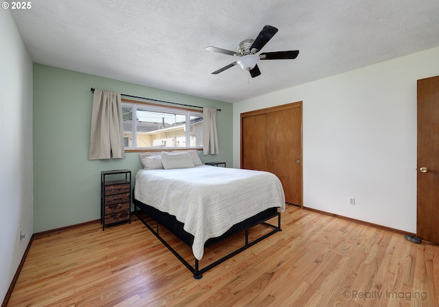 bedroom featuring a closet, baseboards, light wood finished floors, and a textured ceiling