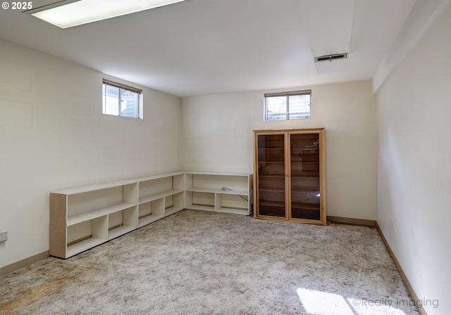 below grade area featuring a wealth of natural light, baseboards, and carpet