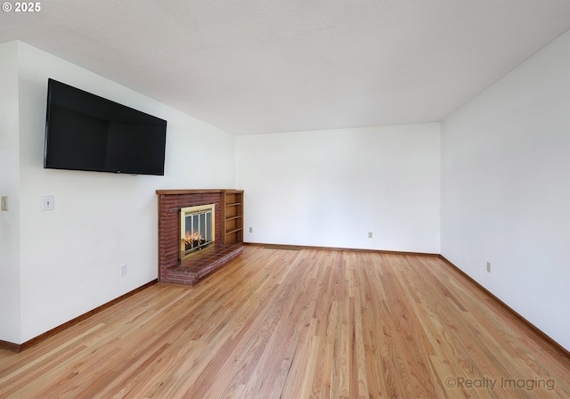 unfurnished living room featuring a fireplace, light wood-style floors, and baseboards