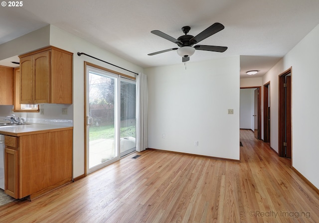 kitchen with light wood finished floors, visible vents, baseboards, light countertops, and a sink