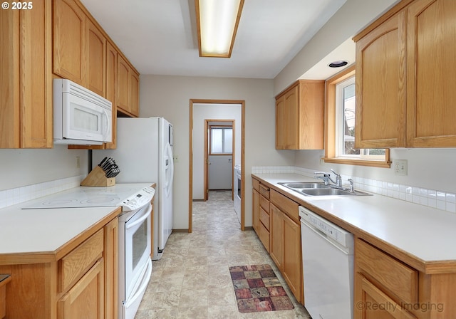 kitchen featuring white appliances, light countertops, baseboards, and a sink