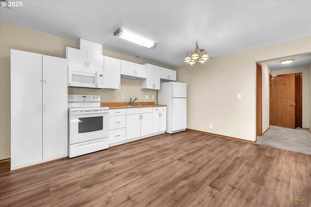 kitchen with an inviting chandelier, white cabinets, a sink, wood finished floors, and white appliances