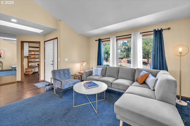 living area featuring vaulted ceiling, baseboards, and wood finished floors