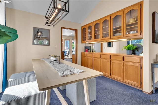 kitchen featuring lofted ceiling, light countertops, brown cabinets, dark carpet, and glass insert cabinets