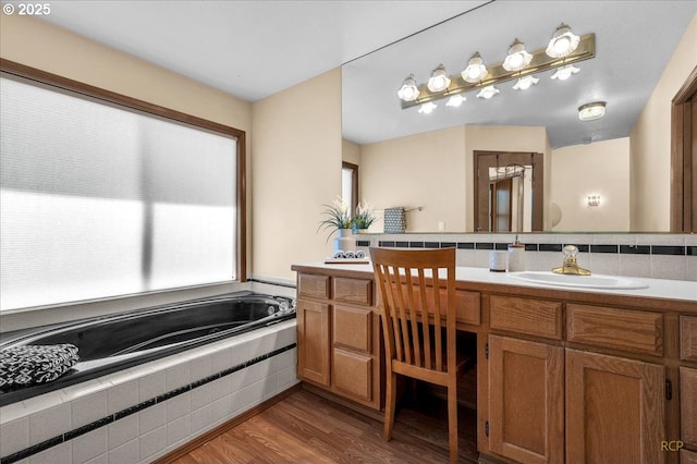 full bathroom featuring tasteful backsplash, a garden tub, vanity, and wood finished floors