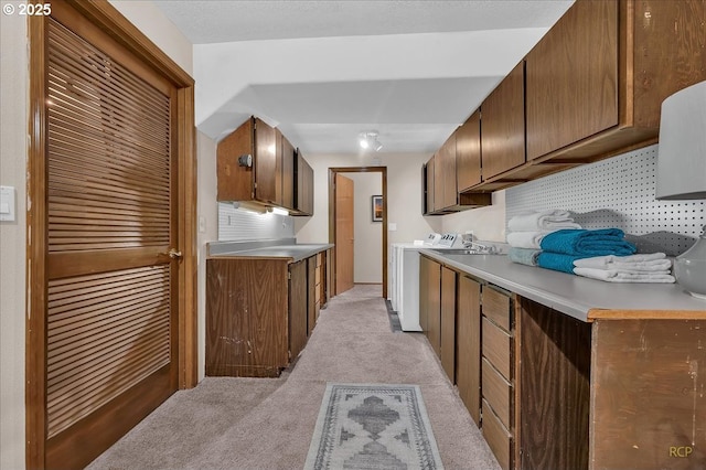 kitchen featuring light countertops, separate washer and dryer, decorative backsplash, and light colored carpet