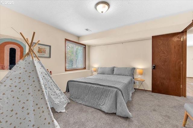 bedroom with carpet floors, visible vents, and a textured ceiling