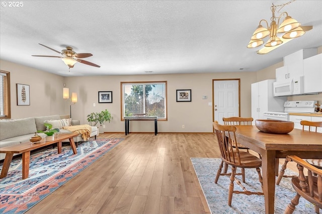 dining room featuring light wood-style floors, a textured ceiling, and ceiling fan with notable chandelier