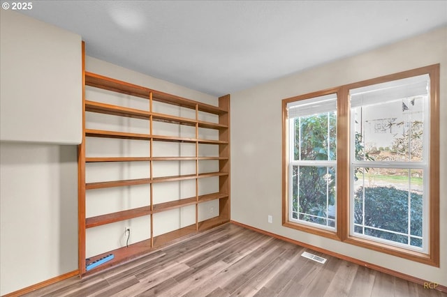 empty room featuring baseboards, visible vents, and wood finished floors