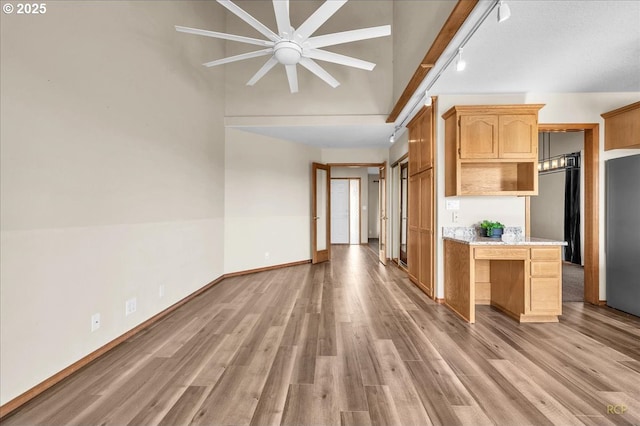 kitchen featuring light wood finished floors, baseboards, light countertops, light brown cabinetry, and track lighting