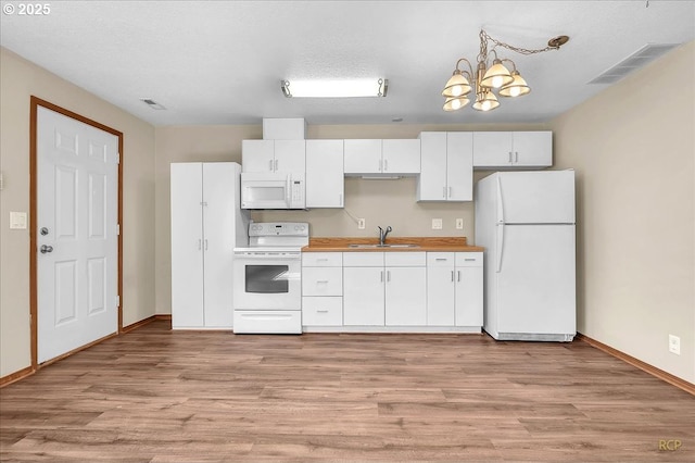 kitchen with white appliances, visible vents, and white cabinets