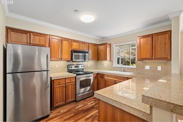 kitchen featuring tile countertops, a sink, appliances with stainless steel finishes, brown cabinets, and backsplash