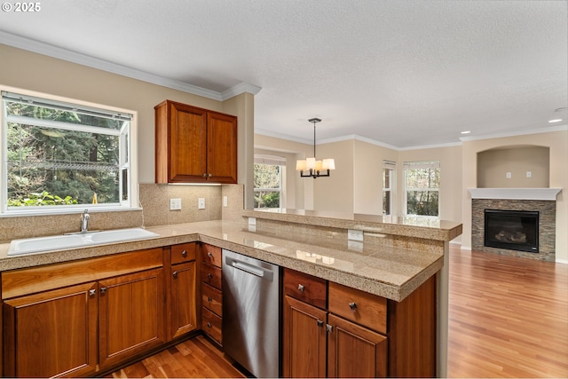 kitchen with light wood-type flooring, a sink, backsplash, dishwasher, and tile counters