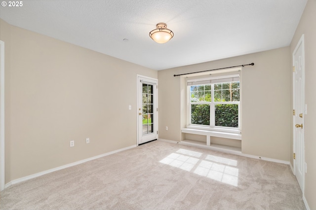 carpeted spare room featuring baseboards and a textured ceiling