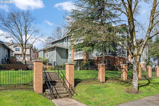 view of front of home featuring a fenced front yard, stairs, and a front lawn