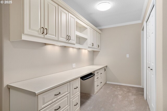 unfurnished office with a textured ceiling, ornamental molding, baseboards, and light carpet