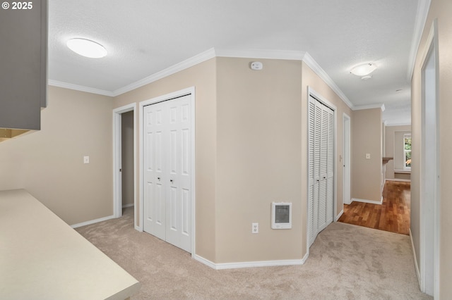 hallway featuring a textured ceiling, carpet flooring, baseboards, and ornamental molding