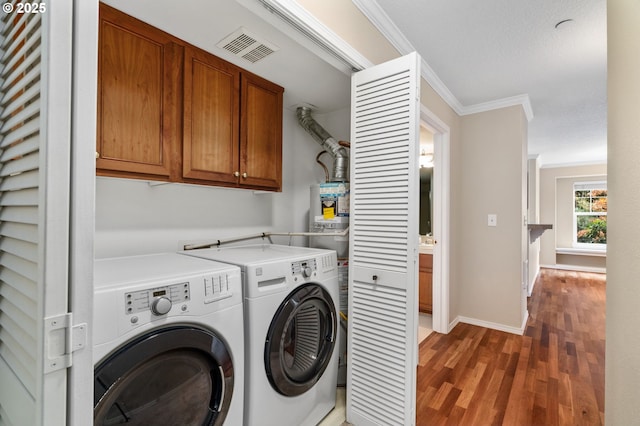 laundry area with visible vents, ornamental molding, cabinet space, light wood-style floors, and washing machine and clothes dryer