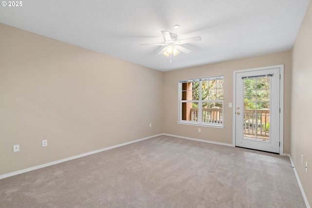 unfurnished room with a textured ceiling, light colored carpet, baseboards, and ceiling fan