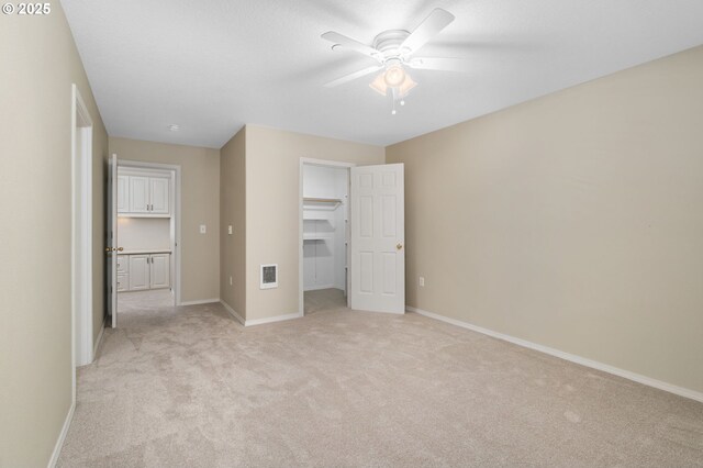 unfurnished bedroom with visible vents, baseboards, light colored carpet, ceiling fan, and a spacious closet