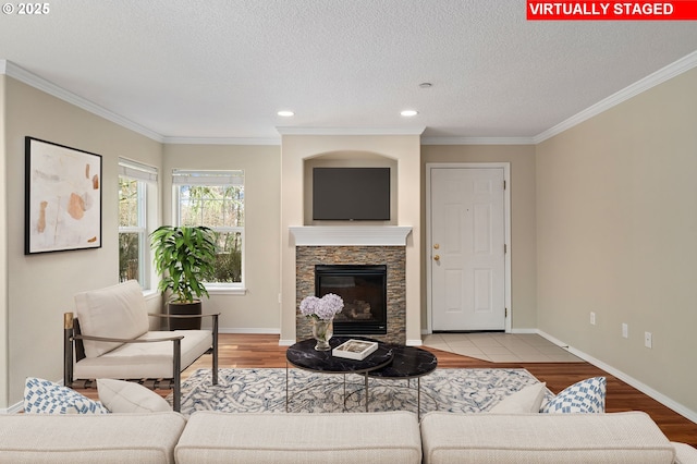 living area featuring ornamental molding, a fireplace, baseboards, and wood finished floors