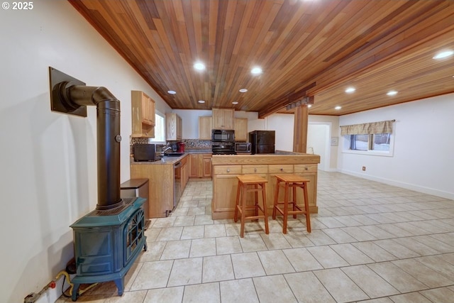 3162 Marine Dr, Astoria, OR 97103 - kitchen with black appliances, wood ceiling, recessed lighting, a breakfast bar, and a wood stove