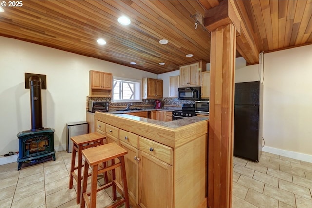 3162 Marine Dr, Astoria, OR 97103 - kitchen with black appliances, wood ceiling, a wood stove, light tile patterned floors, and recessed lighting