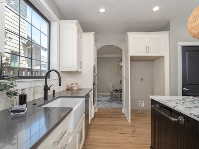 7882 SW Cinnabar, Wilsonville, OR 97070 - kitchen featuring light wood-style floors, arched walkways, plenty of natural light, white cabinets, and recessed lighting