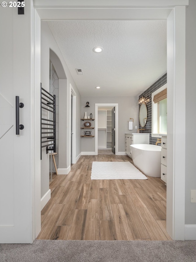 7882 SW Cinnabar, Wilsonville, OR 97070 - bathroom featuring a soaking tub, wood finished floors, a towel warmer, a textured ceiling, and recessed lighting