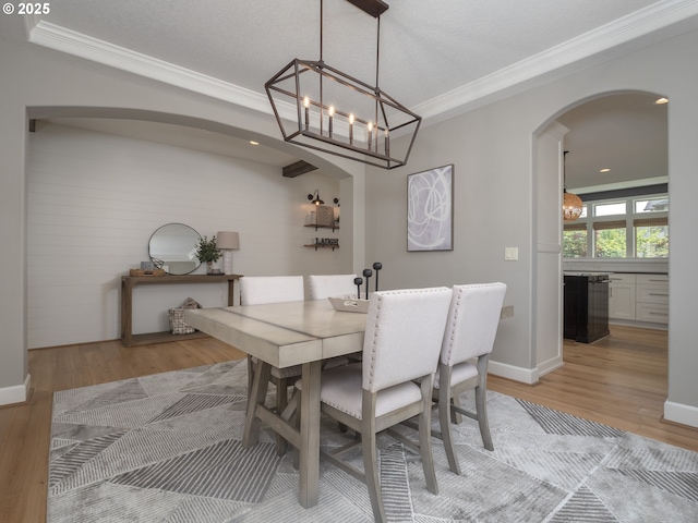 7882 SW Cinnabar, Wilsonville, OR 97070 - dining room featuring arched walkways, a chandelier, crown molding, and light wood-style flooring