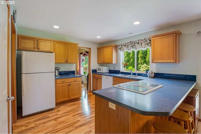 287 SW Oliver Ct, Dundee, OR 97115 - kitchen with white appliances, a sink, dark countertops, light wood-style flooring, and a peninsula