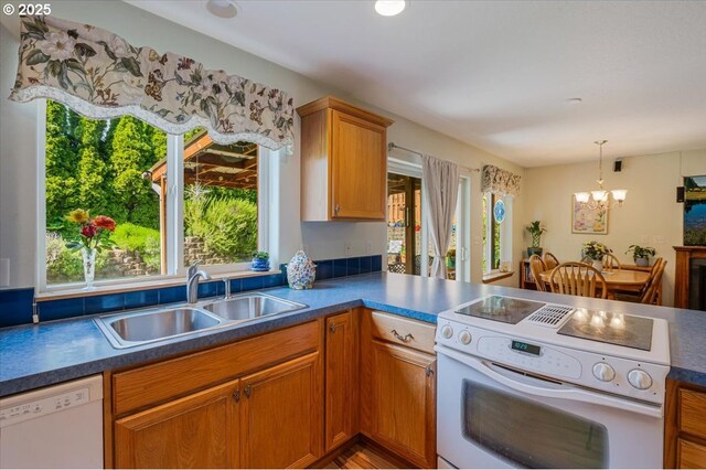 287 SW Oliver Ct, Dundee, OR 97115 - kitchen with white appliances, a sink, a chandelier, a peninsula, and pendant lighting
