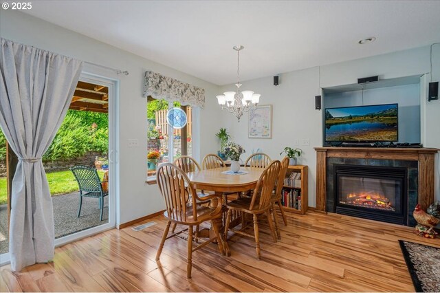 287 SW Oliver Ct, Dundee, OR 97115 - dining room with wood finished floors, a chandelier, a glass covered fireplace, and baseboards